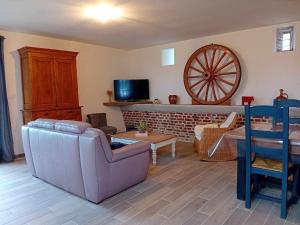 uma sala de estar com um sofá e uma roda na parede em Gite Ferme du Marronnier em Graincourt