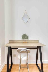 uma mesa de madeira com uma cadeira e uma planta sobre ela em Paris Gentilly appartement tout équipé - RER B em Gentilly