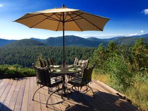 a table and chairs with an umbrella on a deck at Colorado Bed & Breakfast with beautiful views in Evergreen