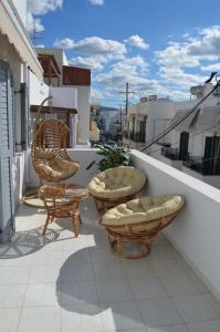 a balcony with two chairs and chairs on a building at Althea Old Town Apartment in Naxos Chora