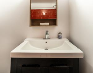 y baño con lavabo blanco y espejo. en Cozy 1 bedroom apartment - 107, en Montreal