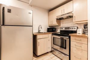 una cocina con electrodomésticos de acero inoxidable y armarios de madera en Cozy 1 bedroom apartment - 107, en Montreal