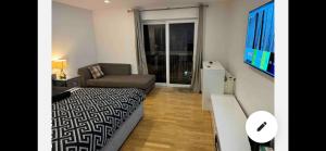 a bedroom with a bed and a couch and a television at En-suite room with a superking size bed and balcony in London