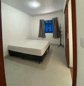 een slaapkamer met een bed in een kamer met een raam bij Casa 2 Quartos 2 Suítes Castelhanos ES in Anchieta