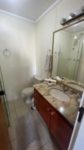 a bathroom with a sink and a toilet and a mirror at Flat Capitania Varam l beira-mar l 2 vagas l Serv Praia in Guarujá