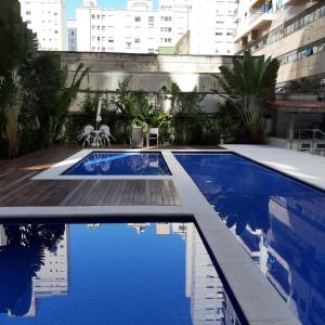a swimming pool with blue water in a building at Flat Capitania Varam l beira-mar l 2 vagas l Serv Praia in Guarujá