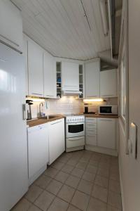 a kitchen with white cabinets and a tile floor at Mökki luonnon keskellä Espoossa in Espoo