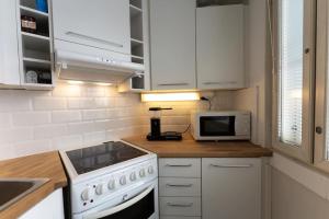 a kitchen with a stove and a microwave at Mökki luonnon keskellä Espoossa in Espoo