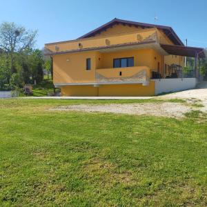 a yellow house with a grass field in front of it at Agriturismo Tenuta Umberto I in Ripacorbaria
