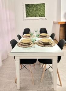 a white table with chairs and plates and wine glasses at Casa la perla de sefarad in Lucena
