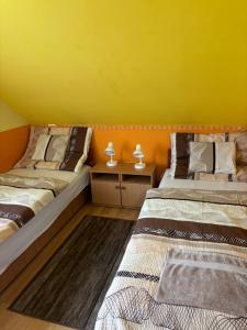 2 camas en una habitación con una pared amarilla en Horvath Vendeghaz, en Hegyeshalom