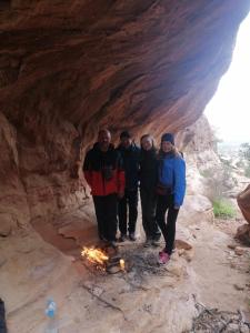 un grupo de personas de pie alrededor de un fuego en una cueva en Dana Nabil Ecu Camp House - Main Gate Dana nature reserve, en Dana