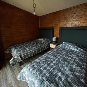 two beds in a room with wooden walls at Cabañas Lakü in Ñilque