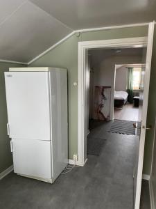 a room with a white refrigerator and a bedroom at En liten lägenhet i centrala Sveg. in Sveg