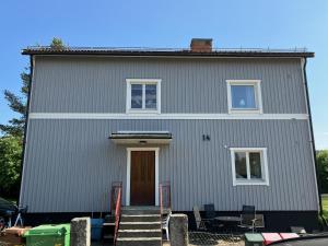 a gray house with a front door and stairs at En liten lägenhet i centrala Sveg. in Sveg
