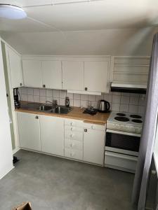 een keuken met witte kasten, een wastafel en een fornuis bij En liten lägenhet i centrala Sveg. in Sveg