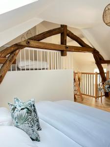 een slaapkamer met een wit bed en houten balken bij Le Gite de Florian in Chablis