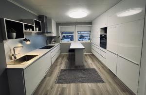 una cocina con armarios blancos y fregadero en Stort og flott hus på Tyholt, en Trondheim