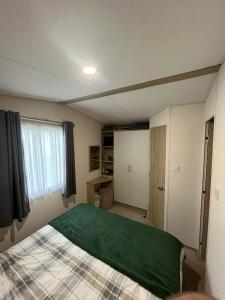 a bedroom with a bed with a green blanket on it at Lemon Grove in Mudeford +11 photos