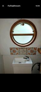 a bathroom with a sink and a round mirror at Cosy, secluded narrow boat in Airton