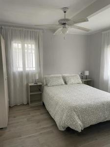 1 dormitorio blanco con 1 cama y ventilador de techo en Preciosa casa entera con patio, en Zarza de Granadilla