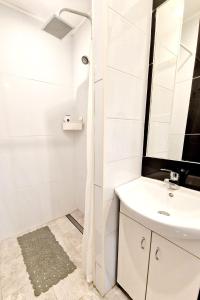 a white bathroom with a sink and a shower at Lawendowy Zakątek Apartament in Kłodzko