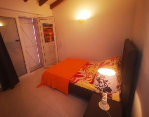 コティ・シアヴァーリにあるVilla Oliviaのベッドルーム1室(オレンジの毛布とランプ付きのベッド1台付)