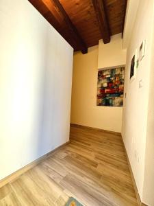 a room with a white wall and wooden floors at Maison Costa Masciarelli in LʼAquila