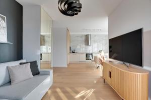 uma sala de estar com um sofá e uma televisão de ecrã plano em Doki - Montownia View by Grand Apartments em Gdansk