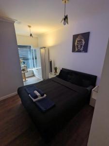 una camera da letto con un letto nero e un asciugamano sopra di Bright & Modern Apartment in Hackney Wick E3 a Londra