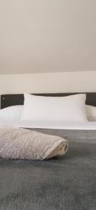 a bed with white sheets and pillows and a rug at Apartments Mario in Drvar