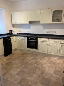a kitchen with white cabinets and a black dishwasher at The Flat in central Kirkby Stephen in Kirkby Stephen