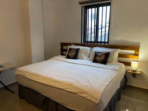 a bedroom with a large white bed with two pillows at Belvoir Apart-Hotel & Residence in Freetown