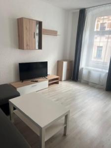 ein Wohnzimmer mit einem weißen Tisch und einem TV in der Unterkunft Zum Bahnhof in Zwickau