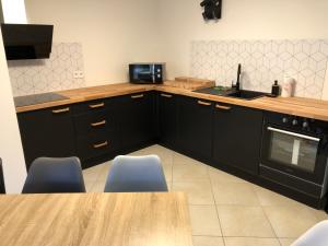 a kitchen with black cabinets and a wooden table at Maison proche du centre ville - Mitoyenne in Saint Die