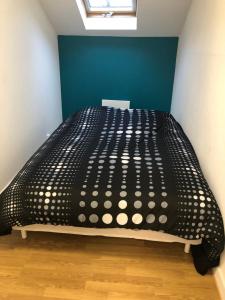 een zwart bed in een kamer met een blauwe muur bij Maison proche du centre ville - Mitoyenne in Saint Die