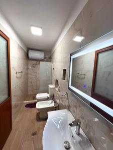 een badkamer met een wastafel, een toilet en een raam bij Villa Dona in Berat