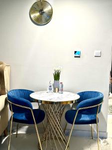 a table with blue chairs and a clock on the wall at Modern 1BR in Dubai South Mag5 with all utilities in Dubai