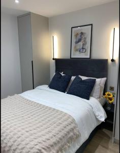 a bedroom with a large white bed with blue pillows at London Luxury Apartments in High Wycombe in Buckinghamshire