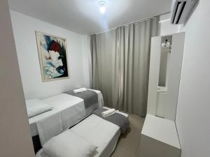um quarto de hospital com três camas e uma janela em Casa em PontaNegra Aconchegante em Natal