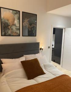 a bedroom with a large white bed with three pictures on the wall at London Luxury Apartments in High Wycombe in Buckinghamshire