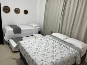 two beds in a room with white walls at Casa em PontaNegra Aconchegante in Natal