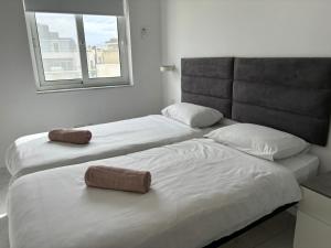 two twin beds in a room with a window at Spacious and Cozy Apartment near St Julians - Short Let Apartments Malta in Is-Swieqi