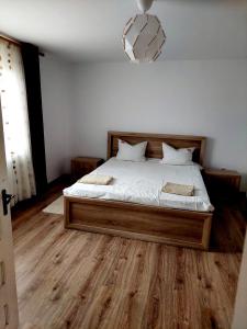 1 dormitorio con 1 cama con sábanas blancas y suelo de madera en Casuta de sub munte, en Buzau