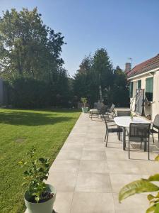 un patio con tavolo e sedie in un cortile di Villa Mesnil St Denis - Idéal Pour les Jeux Olympiques PARIS 2024 a Le Mesnil-Saint-Denis