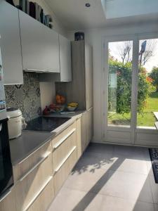 una cucina con armadi bianchi e una porta scorrevole in vetro di Villa Mesnil St Denis - Idéal Pour les Jeux Olympiques PARIS 2024 a Le Mesnil-Saint-Denis