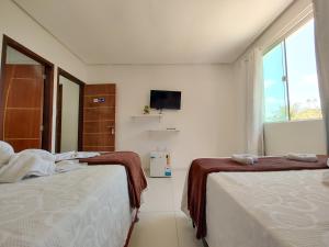 a bedroom with two beds and a tv on the wall at Encantos de Maragogi in Maragogi