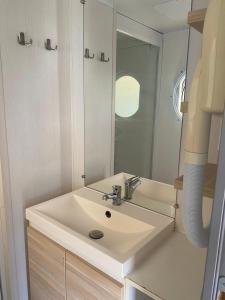 W łazience znajduje się biała umywalka i lustro. w obiekcie Mobil Home w mieście Plouescat