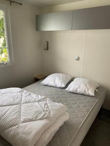 łóżko z dwoma poduszkami w sypialni w obiekcie Mobil Home w mieście Plouescat