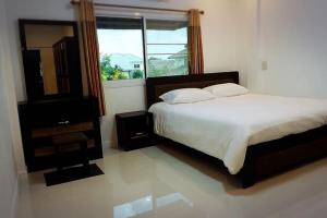 a bedroom with a bed and a mirror and a window at The Living - Holiday Home Phayao in Phayao